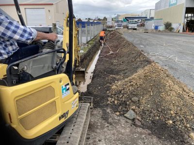 Mini digger excavating a trench on a commercial site in Whangarei