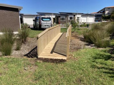 Timber pedestrian bridge with balustrade rails over a gully at a residential subdivision
